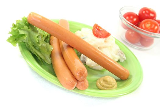 Wiener Sausage with potato salad and lettuce on a white background