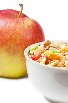 Healthy muesli in a white bowl and apple over white background
