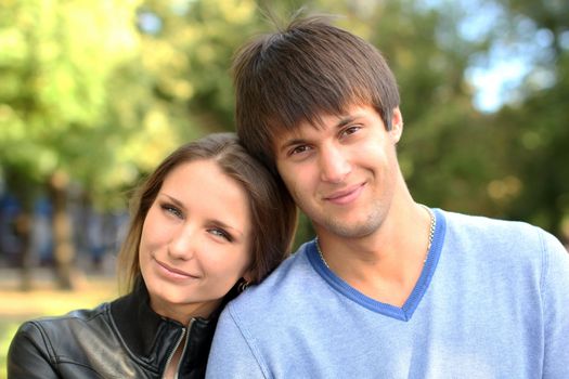 Young couple on a green background of the park.