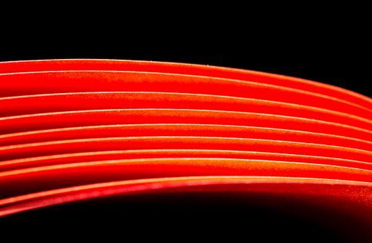 Red A4 paper illuminated with LED lights with black background in landscape orientation