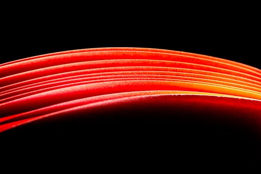 red A4 paper illuminated with lights with black background forming a fiery red curve