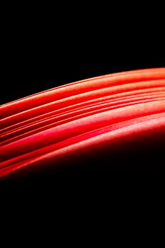 red A4 paper illuminated with lights with black background forming a fiery red curve