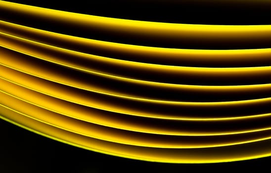 Yellow A4 paper illuminated with LED lights on black background