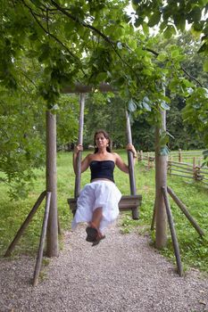 young happy woman on Old wooden swing in  park