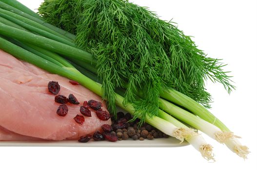 Raw turkey breast with green vegetables and cranberries on plate isolated on white background