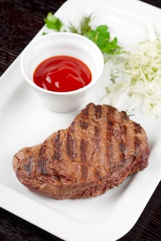 Juicy roasted beef steak with vegetables closeup at plate