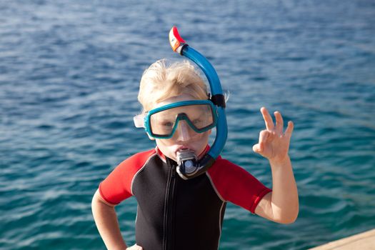 child in a diving mask showing ok
