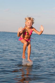 happy girl jumping in water at the evening
