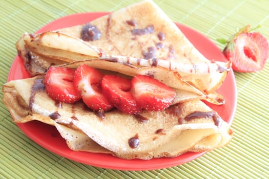 sweet pancakes with strawberries on red plate