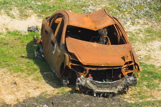 
Front view of the remains of a burnt out car in a field