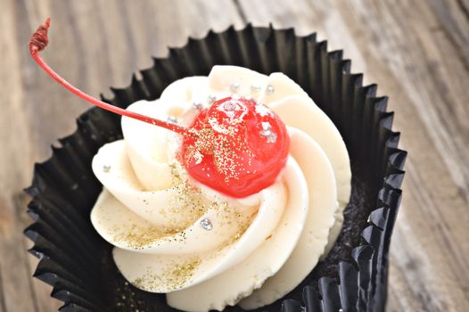 Close up of a cupcake with a red cherry on top