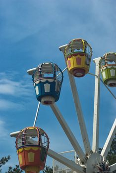 Popular attraction in park - a Ferris wheel on a background of the cloudy blue sky