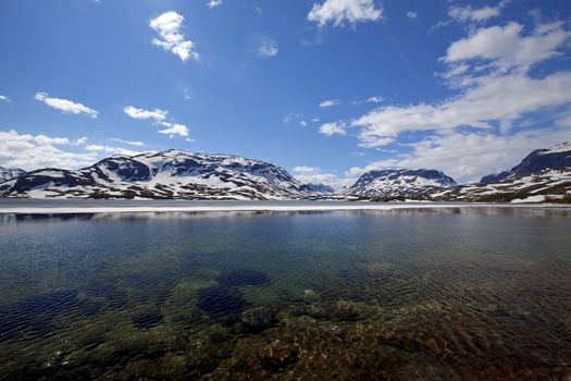 Snowcapped mountains reflecting in the water at Haukeli, Norway