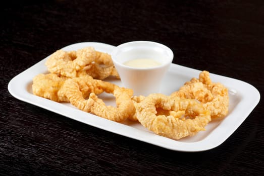 Deep-fried squid with sauce at white plate