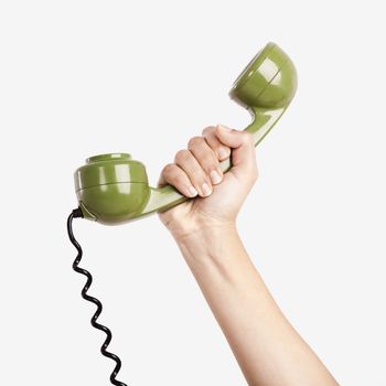 Female hand holding a green handpiece from a vintage telephone