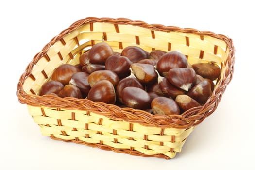 Raw chestnuts in basket over white