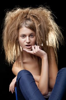 Wild beautiful girl portrait with shaggy hair on a black background posing