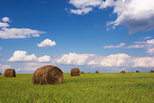 Straw bales on field under blue sky