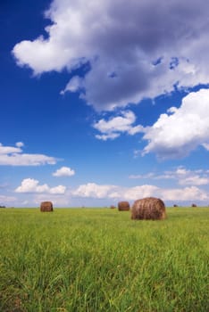 Straw bales on field under blue sky