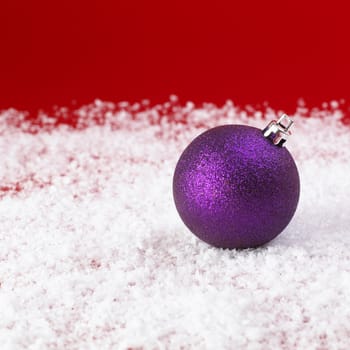 purple Christmas baubles on snow.