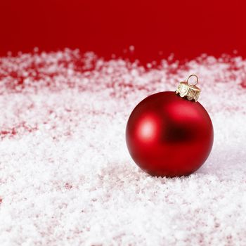 Red Christmas baubles on snow.