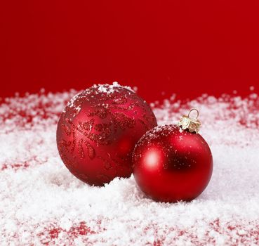 Red Christmas baubles on snow.