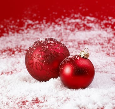 Red Christmas baubles on snow.