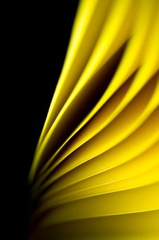 Yellow A4 paper illuminated by LED lights and twisted with black background