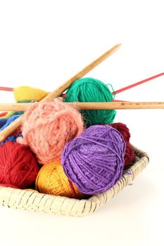 many colorful woolen yarn with knitting needles in a basket