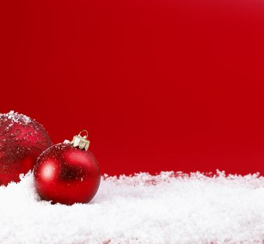 Red Christmas baubles on snow.