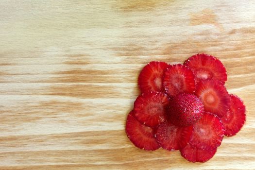 strawberries slices composed as flower on the cutting board in the right bottom corner