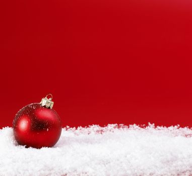 Red Christmas baubles on snow.