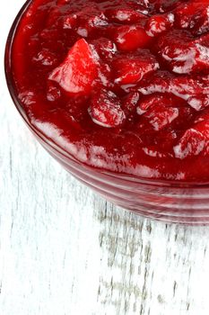 Fresh cranberry apple sauce over a white rustic background. Shallow depth of field.

