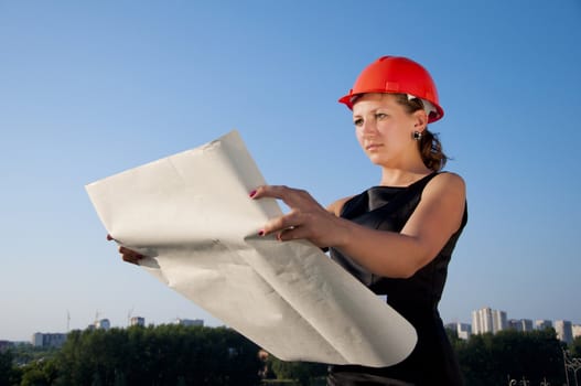 Business woman considers construction plans, blue sky background