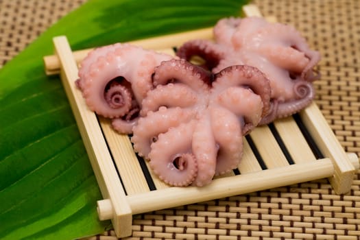 Delicious cooked octopus on wood tray and green leaf