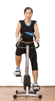 Young woman riding a fitness bicycle in a gym.