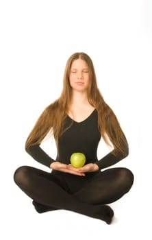 The portrait of a woman in lotus pose with a green apple in her hands
