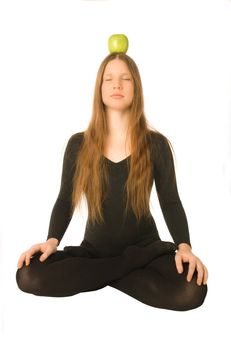 The portrait of a woman in lotus pose with a green apple on her head
