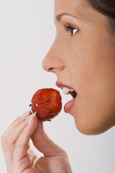 Close-up of a woman mouth bitting into a strawberry.