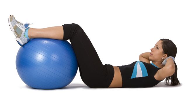 Girl isolated against a white background doing an abdominal exercise with a gym ball.