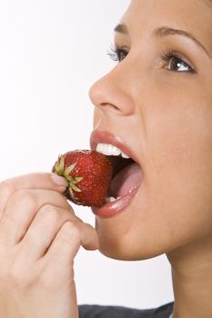 Close-up of a woman mouth bitting into a strawberry.