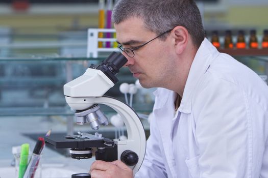 Male researcher looking through a microscope in a laboratory.Shot with Canon 70-200mm f/2.8L IS USM