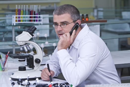 A male researcher using a mobile phone at his workplace in the laboratory.Al the inscriptions are mine.