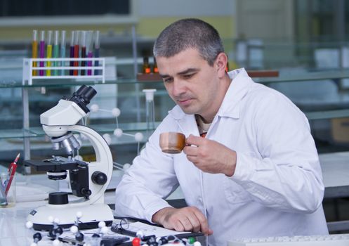Researcher drinking a cup of coffee at his workplace in a laboratory.