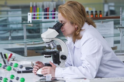 Female researcher looking through microscope in a laboratory.