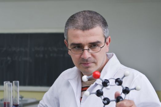 Male researcher looking at a model of a molecule.