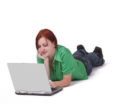 Redheaded teenager lying down in frot of a laptop.