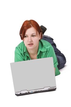 Portrait of a smilling redheaded teenage girl lying down in front of a laptop.