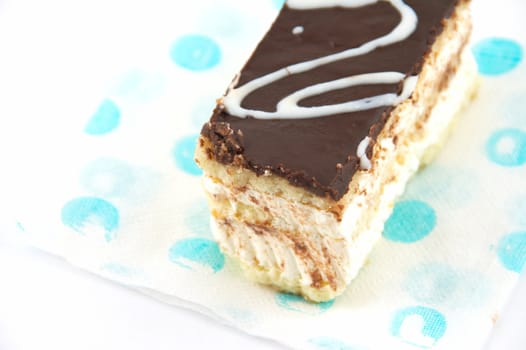 Cake under a layer of the chocolate, laying on a napkin