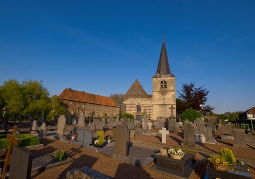 graveyard on a sunny day and blue sky with a little medieval church in the back
